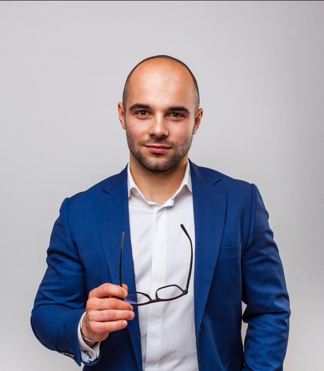 Patryk Borzęcki - portret studyjny z okularami w dłoni